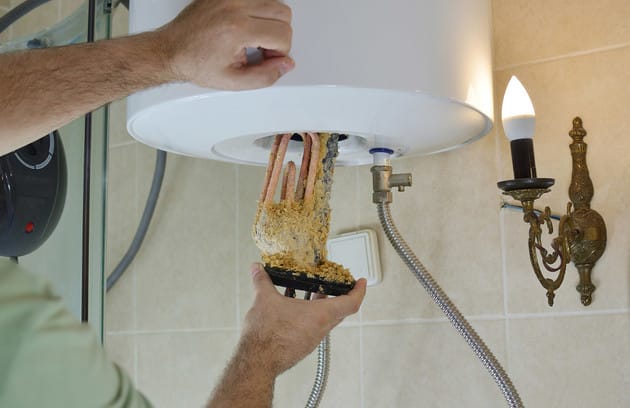 Technician removing mineral buildup from a water heater in Escondido