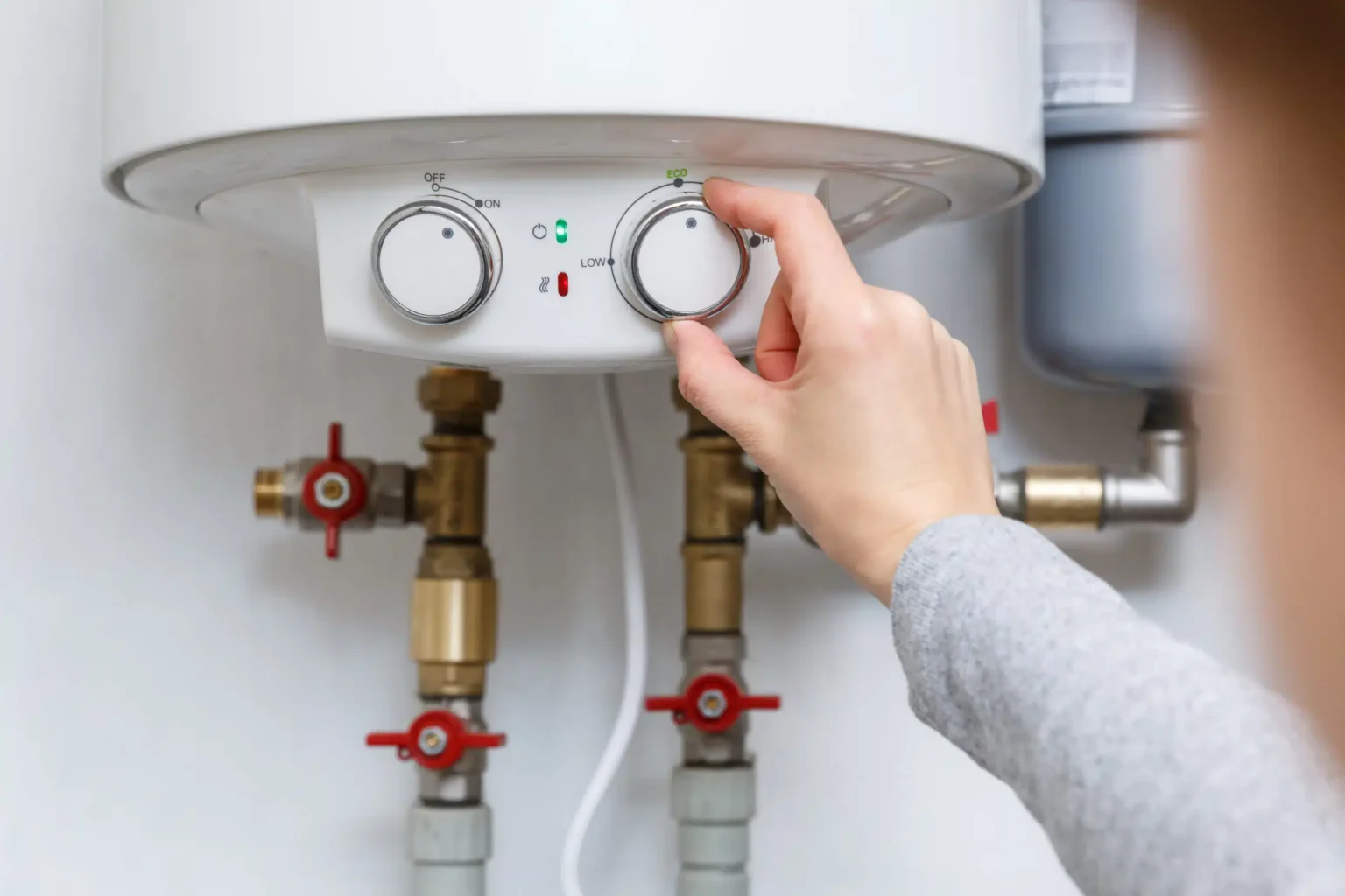 Homeowner adjusting the temperature controls on a water heater in Escondido